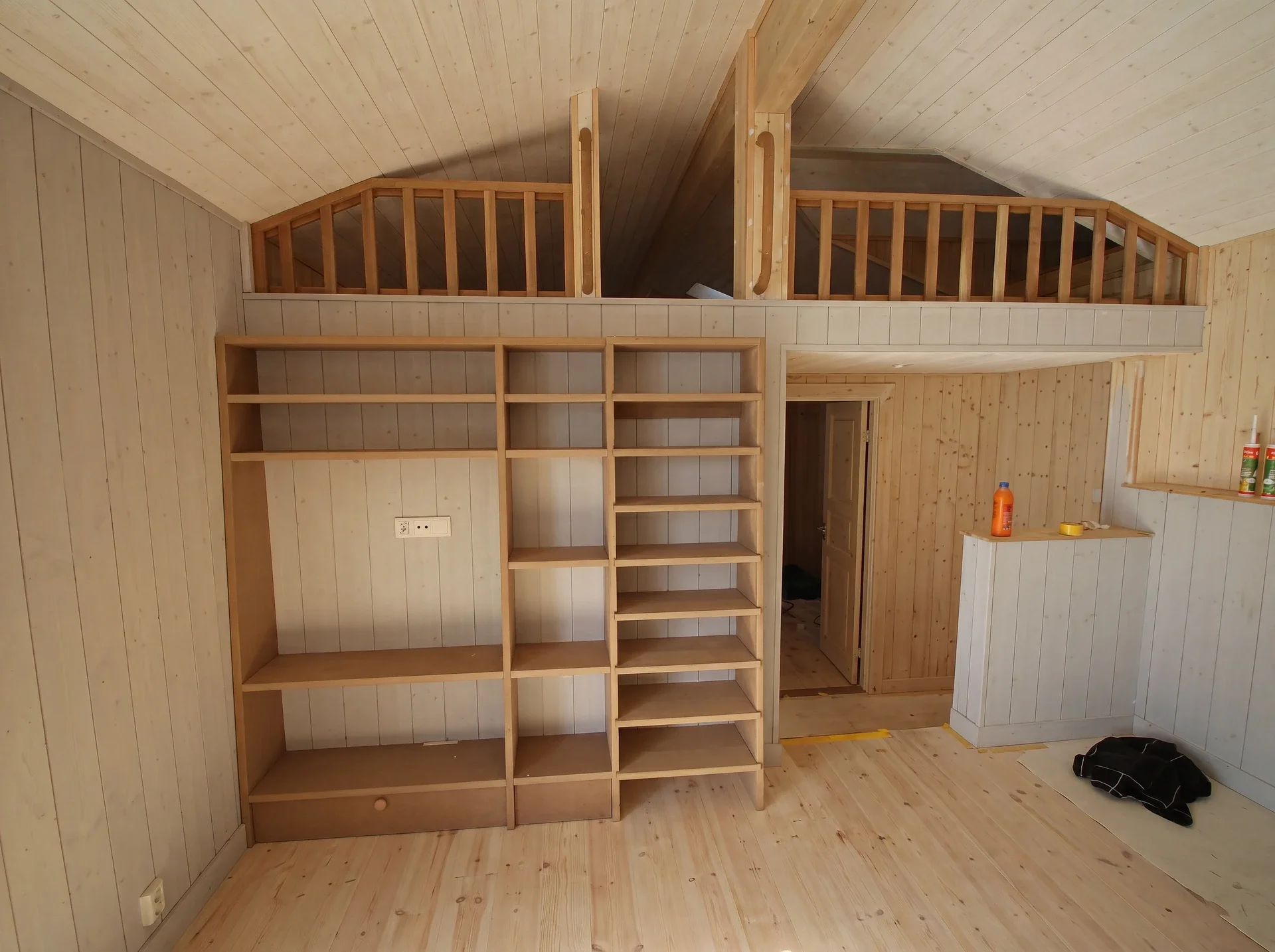 Loft sovplats med trähylla och trappa i ljust trähus