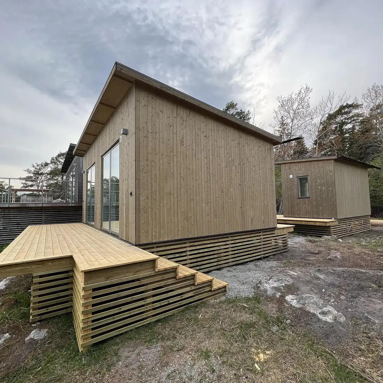 Moderna träfasadshus med altaner och stora fönster under molnig himmel.