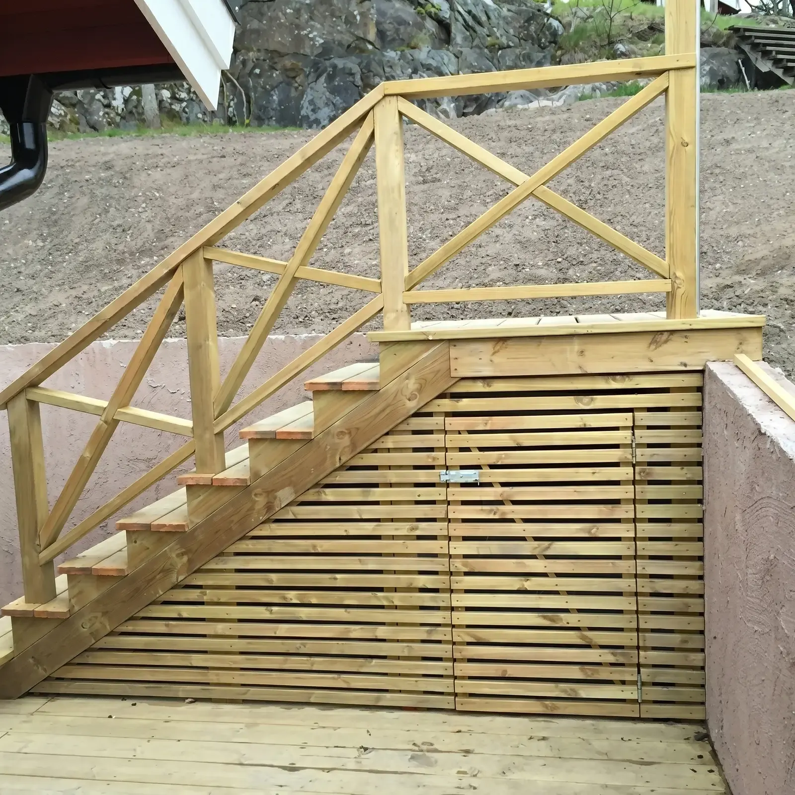 Trätrappa med spjälräcke och horisontella ribbor under trappan.