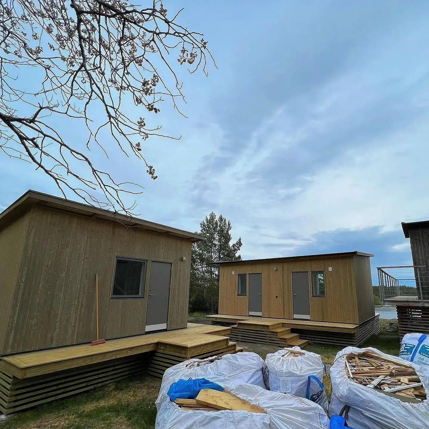 Trähus med altaner under uppbyggnad med byggmaterial i förgrunden.