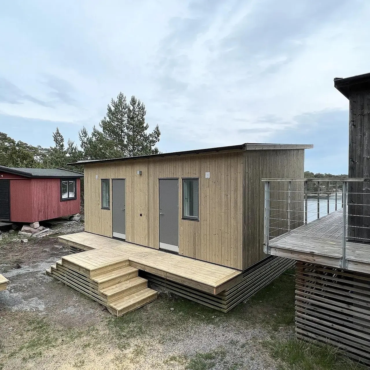 Nybyggt trähus med entrétrappa vid vattenbryn med brygga.