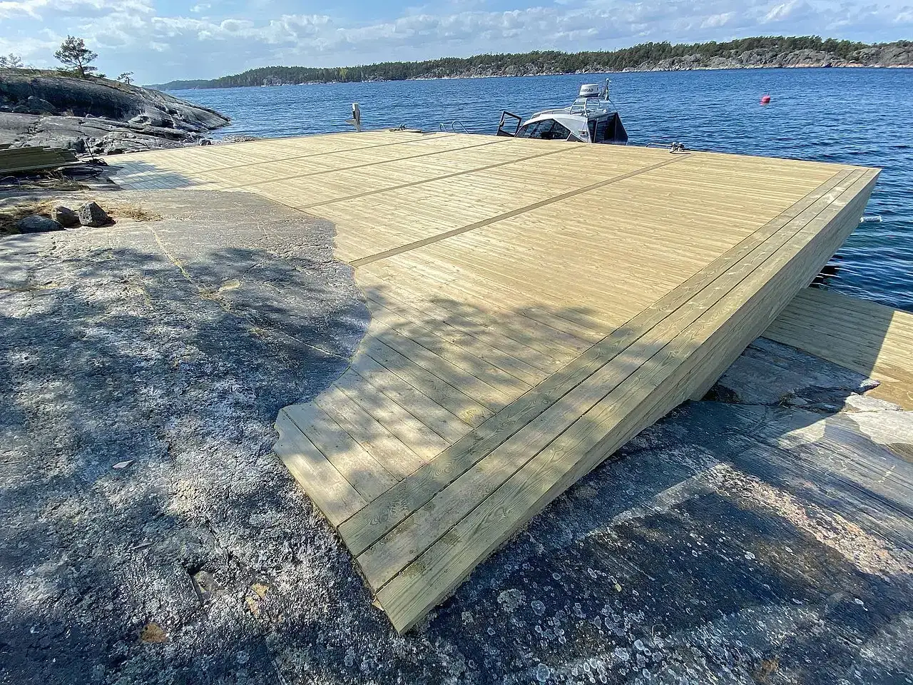 Gårdsplan med oregelbunden stenmosaik mellan bruna byggnader.